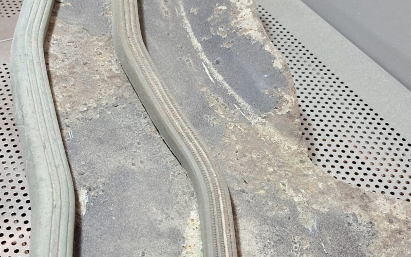Rusted metal motorcycle floorboard with raised grip strips, showing corrosion before restoration.