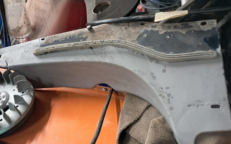 Partially cleaned and sandblasted motorcycle side panel with rubber trim still attached.